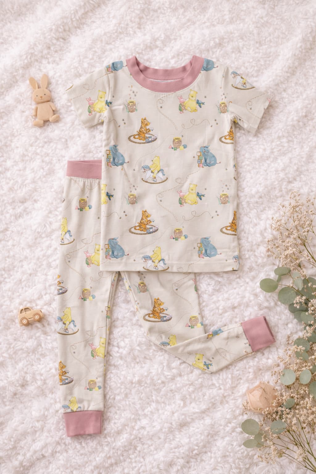 Bamboo pajamas set with short sleeves top and long pants. The print features classic Pooh and firends on a soft cream background with blush as the coordinating color.